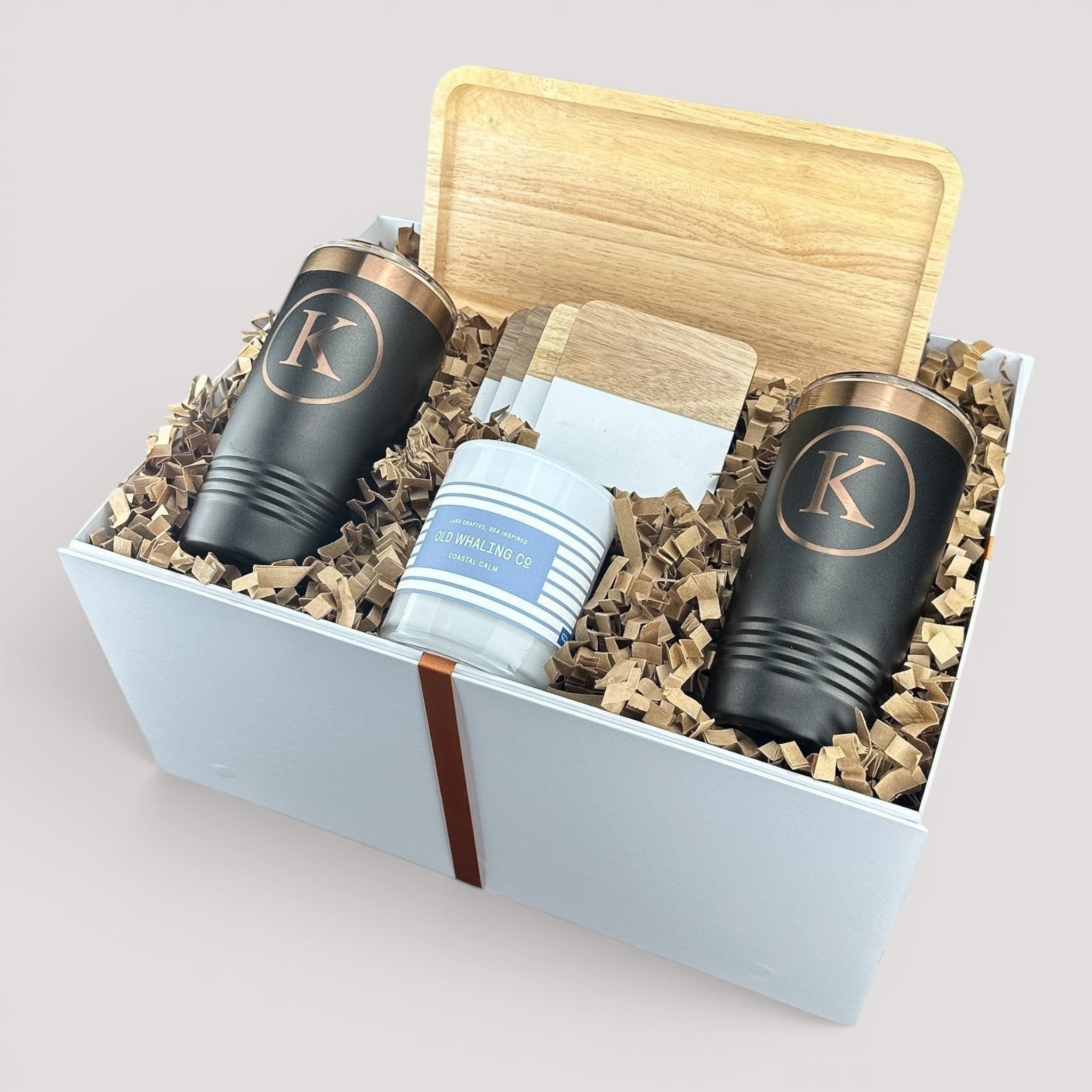 Closing Day Gifts personalized housewarming set featuring a rubber wood tray, two black tumblers, and a scented candle.