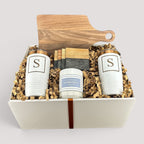 Closing Day Gifts personalized walnut cutting board, white tumblers, marble coasters, and candle in a keepsake box.