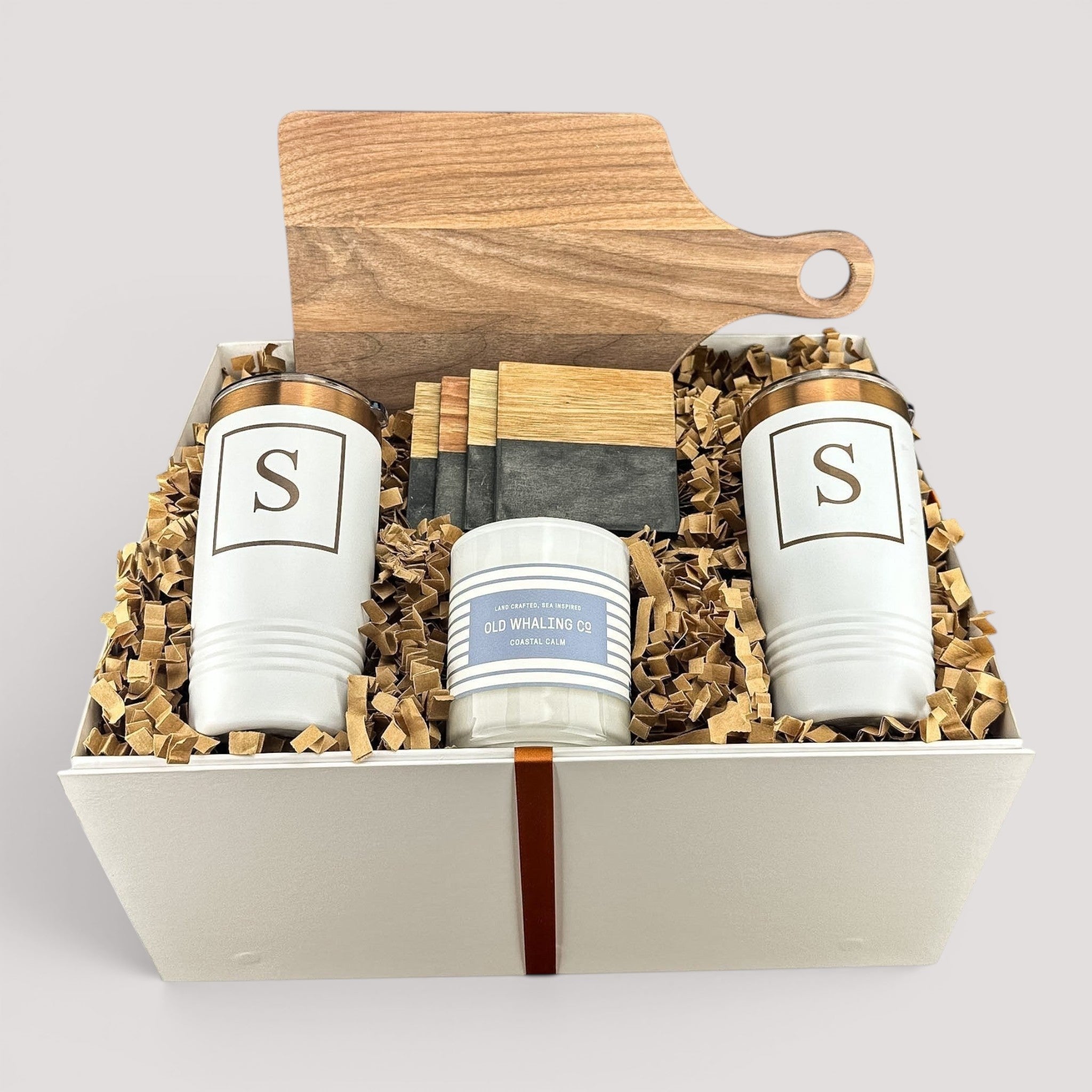 Closing Day Gifts personalized walnut cutting board, white tumblers, marble coasters, and candle in a keepsake box.