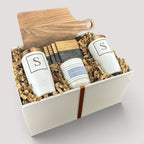 Closing Day Gifts personalized housewarming set with walnut cutting board, white tumblers, marble coasters, and candle.