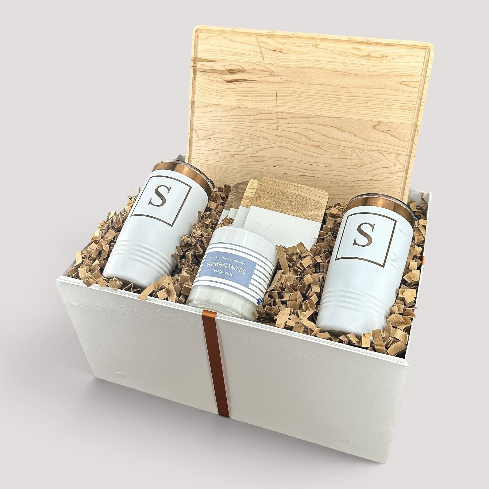 Closing Day Gifts personalized maple cutting board, engraved tumblers, marble coasters, and candle in a gift box.