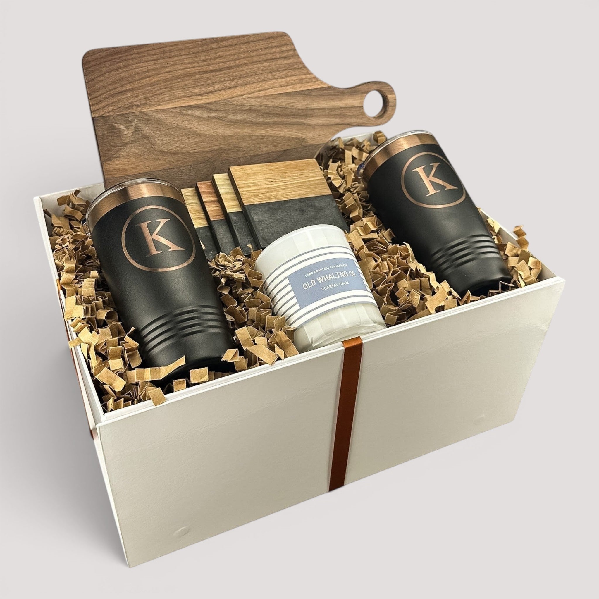 Closing Day Gifts personalized walnut cutting board, black tumblers, marble coasters, and candle in a keepsake box.