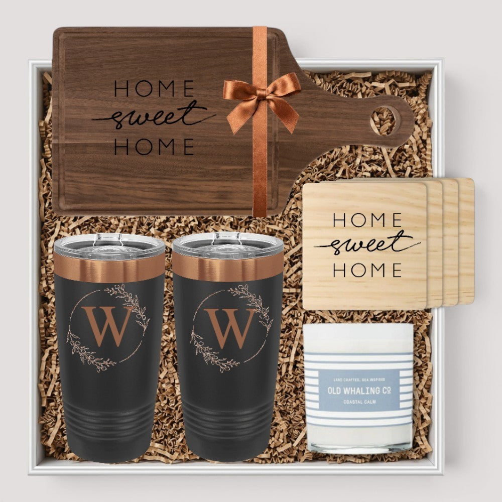 Closing Day Gifts personalized walnut cutting board, engraved tumblers, marble coasters, and candle in a gift box.