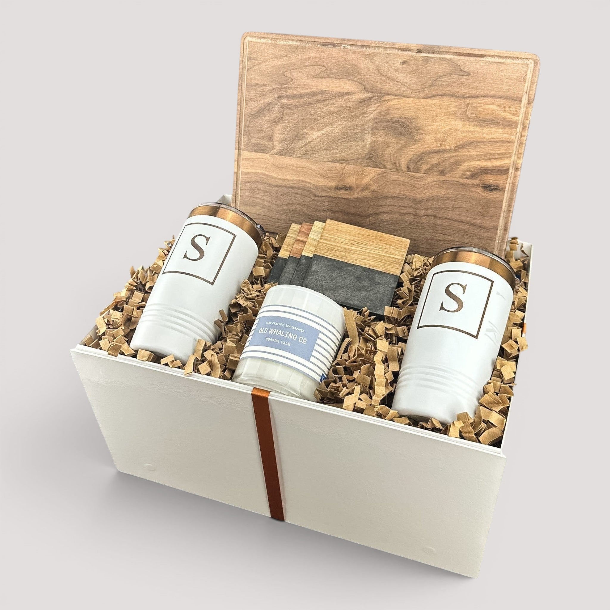 Closing Day Gifts personalized walnut cutting board, engraved tumblers, marble coasters, and candle in a gift box.