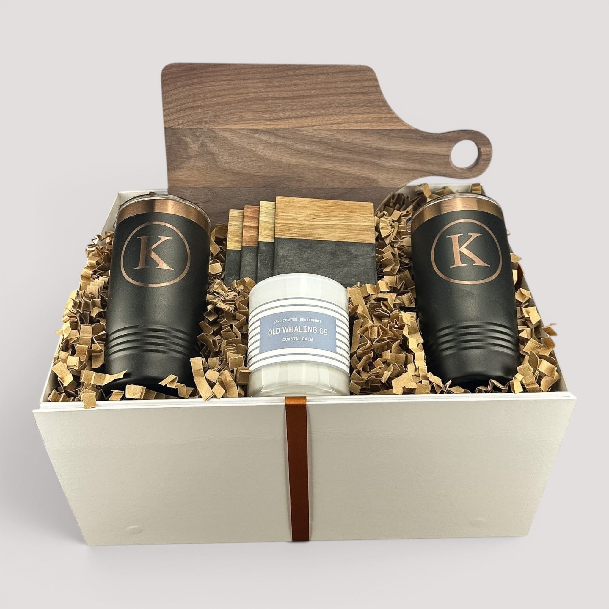 Closing Day Gifts personalized walnut cutting board, engraved tumblers, marble coasters, and candle in a keepsake box.