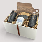 Closing Day Gifts personalized walnut cutting board, black tumblers, marble coasters, and candle in a keepsake box.