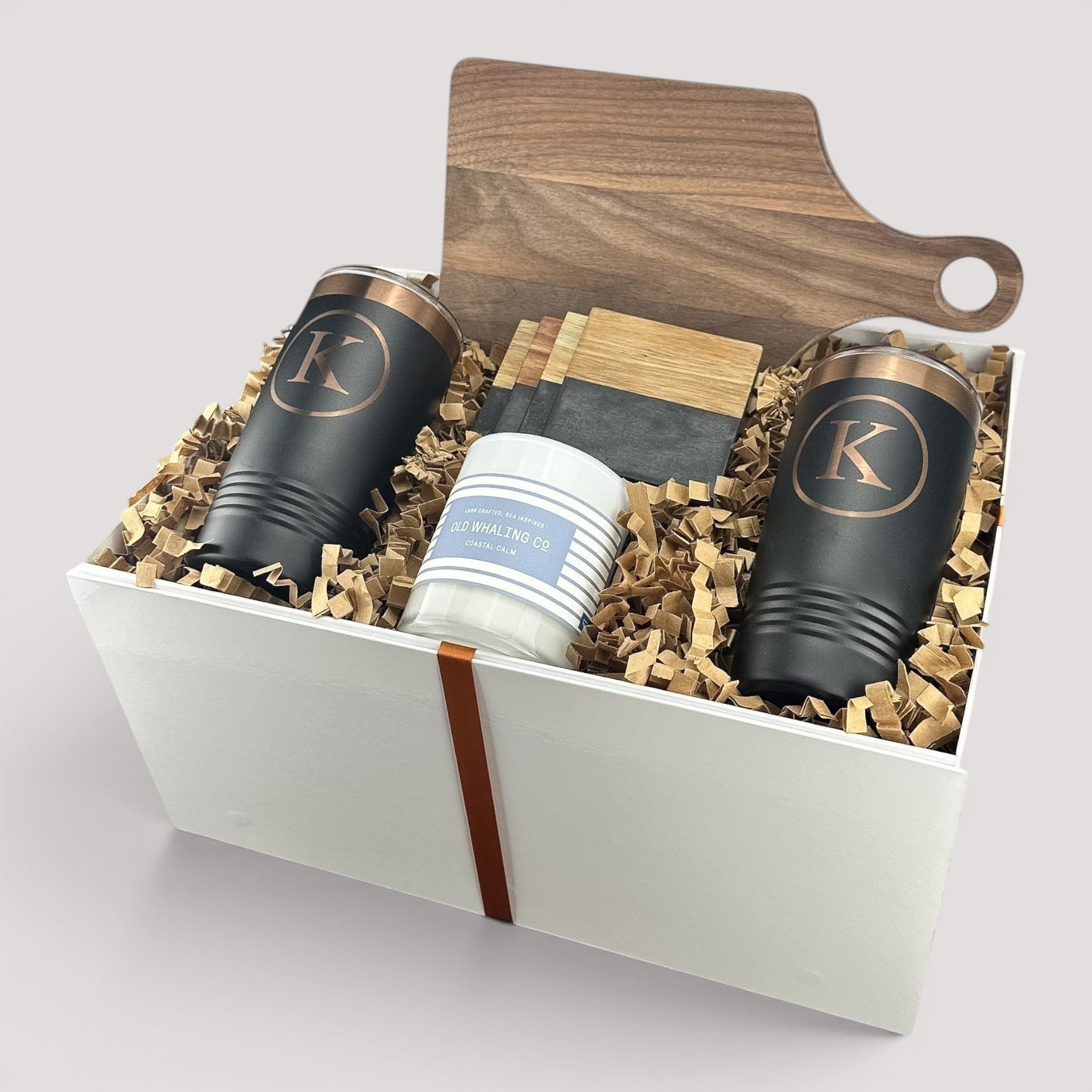 Closing Day Gifts personalized walnut cutting board, black tumblers, marble coasters, and candle in a keepsake box.